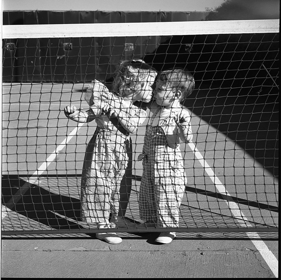 Vivian Maier, Two Children Kissing at Tennis Net, Los Angeles, August 1955